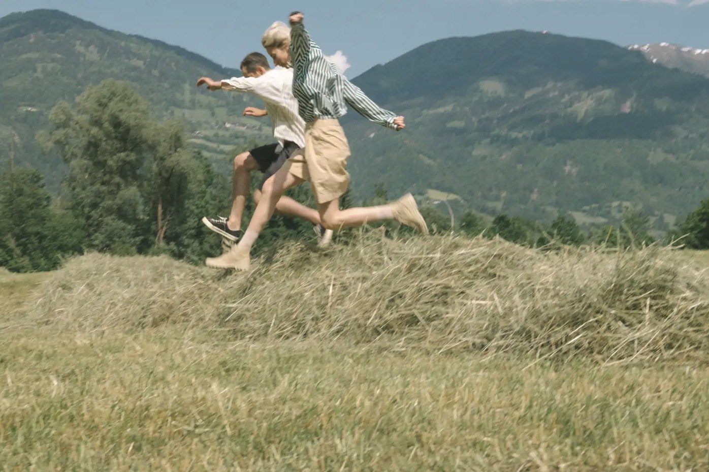 Two friends leaping through a meadow